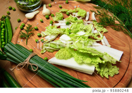 vegetables on a wooden kitchen board, green onions, dill and peas, sliced cabbage on a wood background, concept of fresh and healthy food, still life 93880248