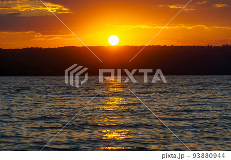 sunset over the lake, bright sun reflected in the waves, glare on the water, beautiful summer landscape 93880944