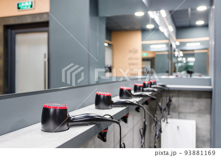 Close up of stand in washroom in gym on which are placed in row many hair dryers. Close up of stand in washroom in gym on which are placed in row many hair dryers. 93881169