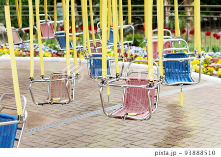 Empty hanging seats of a children's carousel in an amusement park. Selective focus. Empty hanging seats of a children's carousel in an amusement park. Selective focus. 93888510