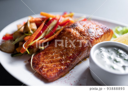 fresh red grilled salmon steak with vegetable salad and sweet sauce, closeup fresh red grilled salmon steak with vegetable salad and sweet sauce, closeup 93888893