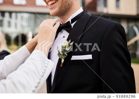 The bride corrects the groom's black tie from a tuxedo The bride corrects the groom's black tie from a tuxedo 93889296