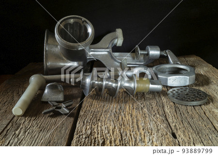 Details of a metal meat grinder on an old wooden board 93889799