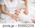 Family, motherhood, parenting, people and child care concept. Happy mother holding hands with adorable baby. 93892256