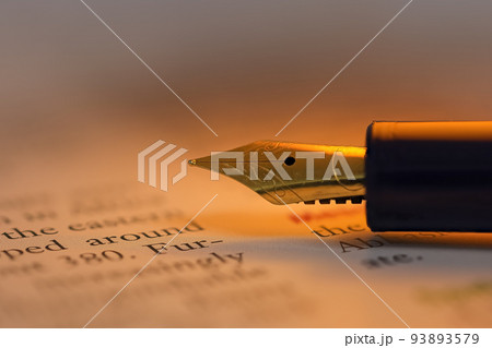 Fountain pen on a historic book backlit with yellow light 93893579