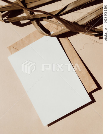 Blank white card, envelope and part dry palm leaf on beige background top view. Blank white card, envelope and part dry palm leaf on beige background top view. 93895166
