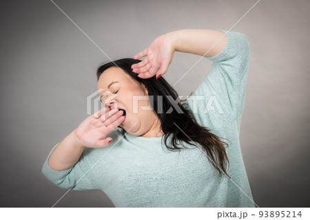 Adult tired woman stretching her arms up Adult tired woman stretching her arms up 93895214