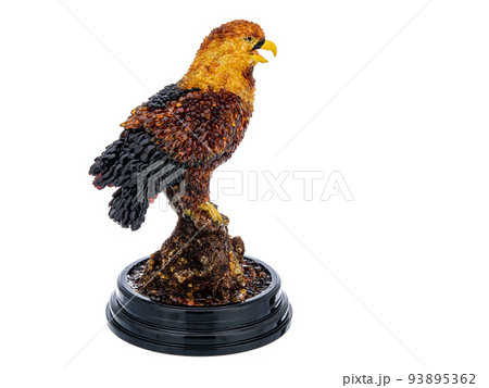 Figurine, statuette an eagle, hawk, falcon on stand on white background. Wild bird sculpture inlaid with natural amber stones. Use for interior design. 93895362