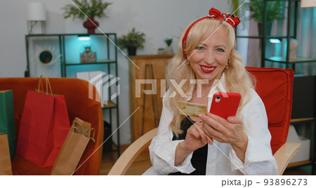 Happy shopaholic senior old grandmother woman making online payment with credit card, purchase order Happy shopaholic senior old grandmother woman making online payment with credit card, purchase order 93896273