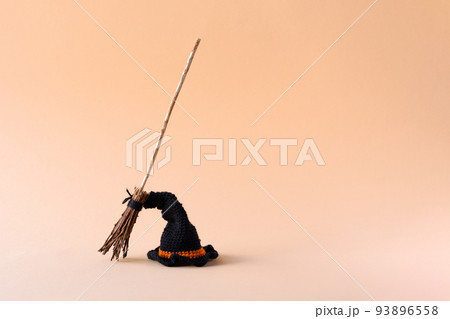 Halloween concept. A black hat and a witch's broom on an orange background, front view, copy space Halloween concept. A black hat and a witch's broom on an orange background, front view, copy space 93896558