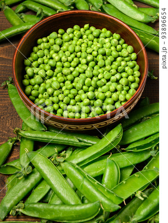 green sweet peas on a dark wooden background, still life, concept of fresh and healthy food green sweet peas on a dark wooden background, still life, concept of fresh and healthy food 93896654