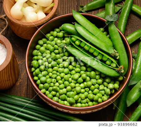 green sweet peas on a dark wooden background, onion, salt, still life, concept of fresh and healthy food 93896662