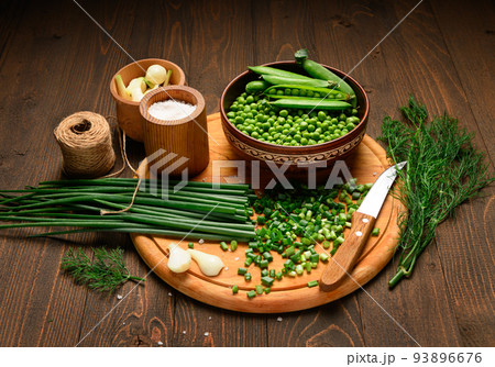green sweet peas on a dark wooden background, onion, salt, still life, concept of fresh and healthy food 93896676