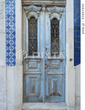 Lisbon, Portugal, October 24, 2021: view of old blue wooden door with ceramic tiles at Lisbon center at Santa Maria Maior district. Lisbon, Portugal, October 24, 2021: view of old blue wooden door with ceramic tiles at Lisbon center at Santa Maria Maior district. 93897940