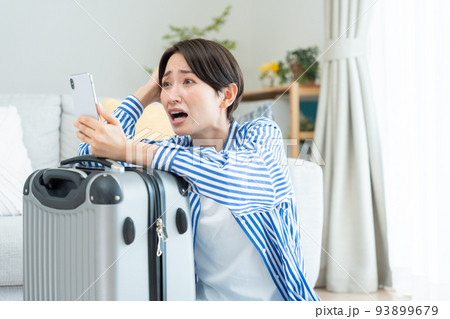 旅行の準備をするミドル女性（スマホ・予約・キャンセル・問題） 93899679