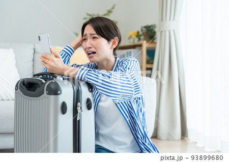 旅行の準備をするミドル女性（スマホ・予約・キャンセル・問題） 93899680