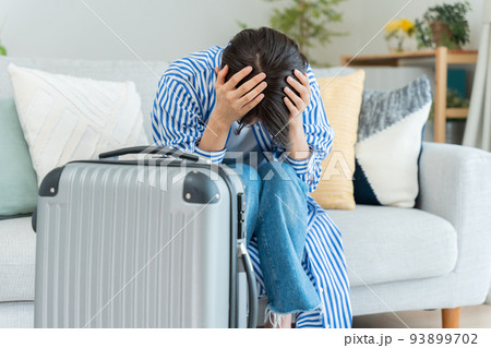 旅行の準備をするミドル女性（落ち込む・ショック・キャンセル） 93899702