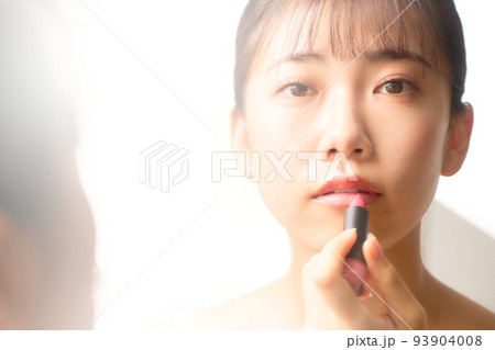 鏡を見ながらリップを塗る若い女性　ビューティー　イメージ 93904008