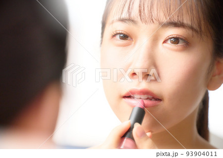 鏡を見ながらリップを塗る若い女性　ビューティー　イメージ 93904011