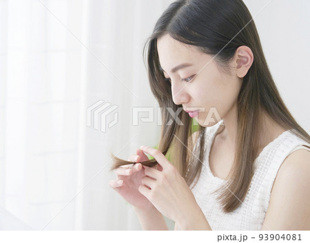 リビングで毛先を見る女性 93904081
