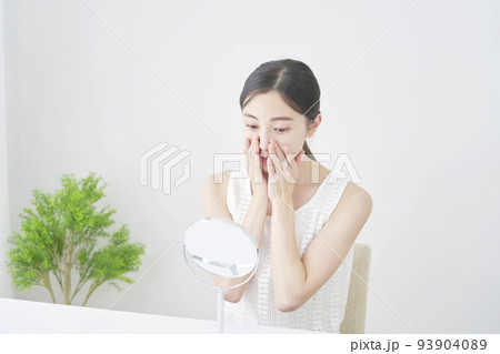 リビングで顔のスキンケアをする女性 93904089