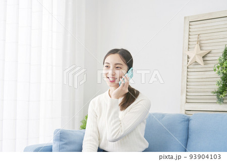 リビングでスマホで電話する女性 93904103