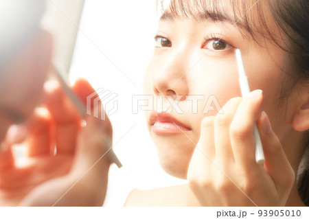 鏡を見ながらアイメイクをする若い女性　ビューティー　イメージ 93905010