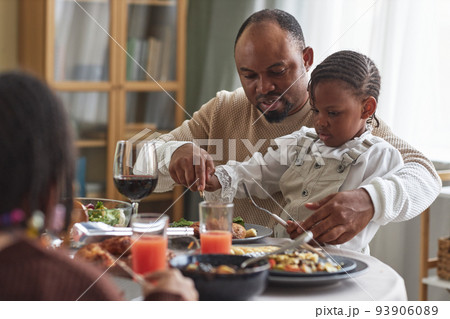 Father helping his child to eat meal 93906089