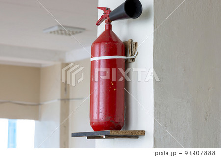 Portable hand-held fire extinguisher mounted on the wall inside the room 93907888