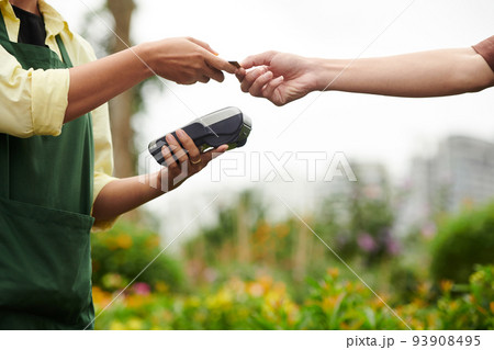 Customer giving credit card to flower nursery worker to pay for order 93908495