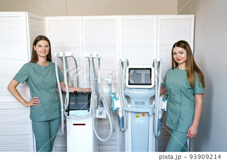 Two women specialists in hardware cosmetology stand in massage room at laser 93909214