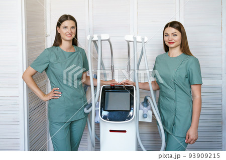 Two women specialists in hardware cosmetology stand in massage room at laser 93909215