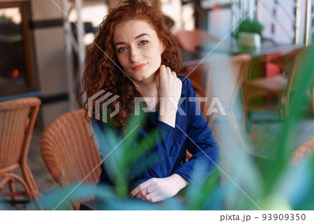 Portrait happy smiling pretty redhead girl sitting in street cafe or co-working Portrait happy smiling pretty redhead girl sitting in street cafe or co-working 93909350
