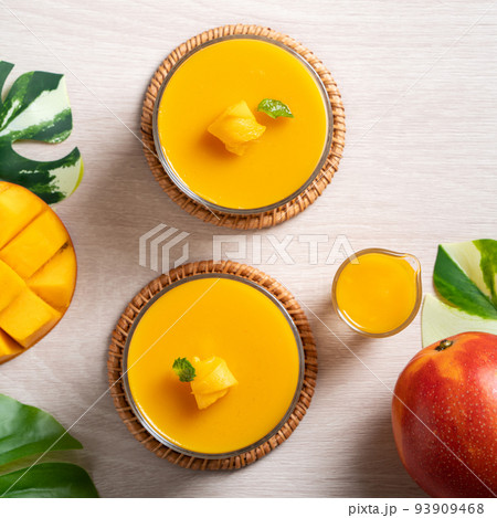 Delicious mango panna cotta mousse pudding on white table background. Delicious mango panna cotta mousse pudding on white table background. 93909468