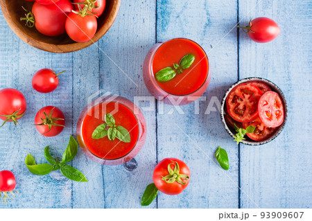 Fresh tomato juice with basil leaves in glasses on the table. Homemade organic drinks. Top view Fresh tomato juice with basil leaves in glasses on the table. Homemade organic drinks. Top view 93909607