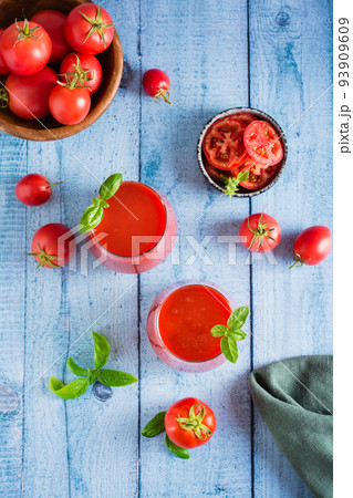 Tomato juice with basil in glasses and vegetables. Organic homemade drinks. Top and vertical view Tomato juice with basil in glasses and vegetables. Organic homemade drinks. Top and vertical view 93909609