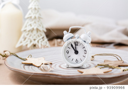 Concept Countdown on Christmas night. Table setting. Alarm clock five to twelve on a plate and christmas eco decorations on the table 93909966