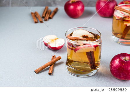 Homemade fresh apple cider with cinnamon in glass on a gray background. Warming winter drinks. Copy space Homemade fresh apple cider with cinnamon in glass on a gray background. Warming winter drinks. Copy space 93909980
