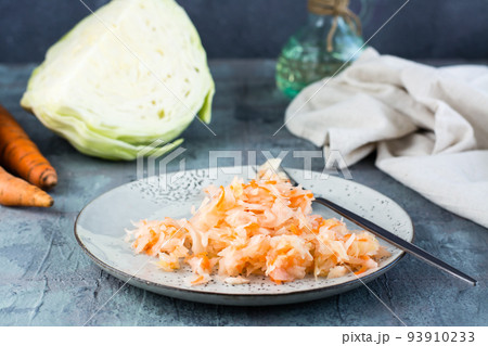 Fresh sauerkraut with carrots and a fork on a plate on the table. Fermentation and a vegetarian diet Fresh sauerkraut with carrots and a fork on a plate on the table. Fermentation and a vegetarian diet 93910233