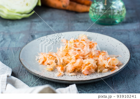 Fresh sauerkraut with carrots on a plate and vegetables on the table. Fermentation and a vegetarian diet 93910241