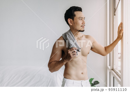 Asian man not wearing top relax after bath in living room in his apartment. Asian man not wearing top relax after bath in living room in his apartment. 93911110