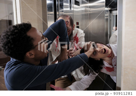 Frightened scared man running from cruel monsters attacking business office, escaping form elevator to eat brain. Bloody spooky walking dead zombies hunting to kill, terror massacre. 93911281