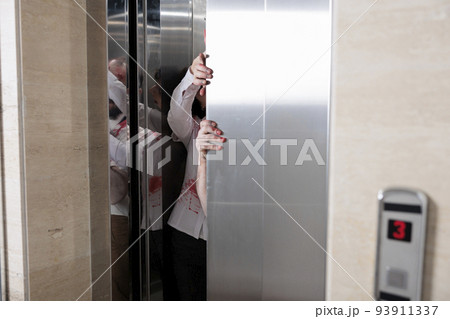 Couple of angry zombies escaping elevator, attacking startup office to attack people with horrific violence. Abusive undead scary monsters eating brain, looking terrifying and cruel. 93911337