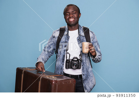 Happy photographer having luggage and DSLR camera getting ready for holiday journey. Joyful photography enthusiast with photo device and baggage going on weekend voyage trip. 93911350