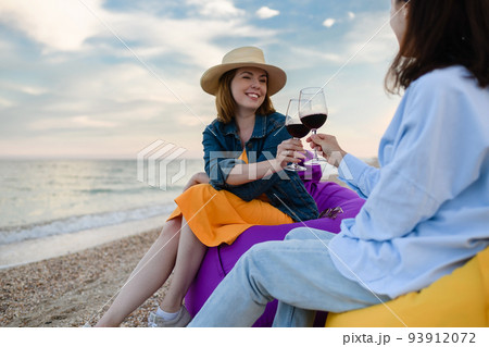 Two pretty young women with glasses of red wine by the sea. Two pretty young women with glasses of red wine by the sea. 93912072