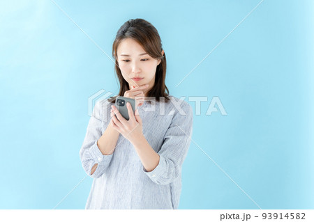 スマートフォンを見る女性 ブルーバック スマートフォンを見る女性 ブルーバック 93914582