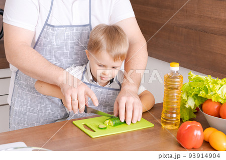 Father and son at home standing in the kitchen together, man smiling 93914904