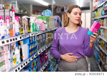Woman choosing hygiene pads at supermarket 93916971