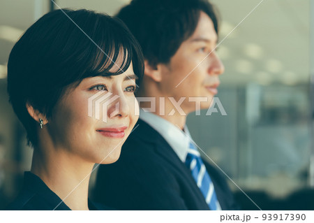 窓際に立つ男女のビジネスマン 窓際に立つ男女のビジネスマン 93917390
