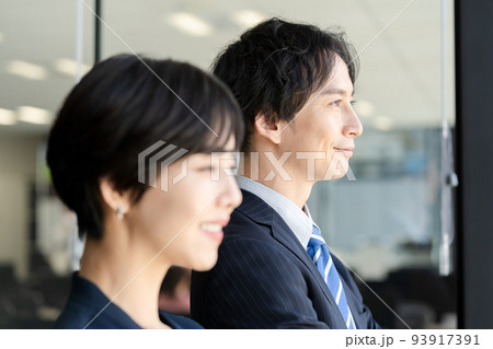窓際に立つ男女のビジネスマン 窓際に立つ男女のビジネスマン 93917391